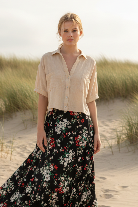 Cream cropped button-up shirt with black floral maxi skirt and coastal beach background