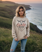 Beige "Country Roads take me home" graphic sweatshirt with female model and coastal cliff background