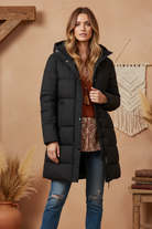 Black puffer coat on model with styled background