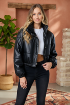 Black puffer jacket on model with styled background