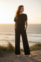 Black wide leg pants with smocked waistband and coastal cliff background