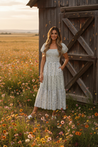 Blue floral stripe smocked puff sleeve midi dress with rustic barn wildflower meadow background