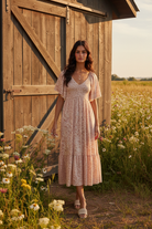 Blush ditsy floral smocked midi dress with rustic barn wildflower meadow background