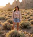 Blush pink cable knit sweater with ribbon detail and desert landscape