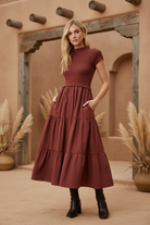 Burgundy tiered midi dress on model with styled background