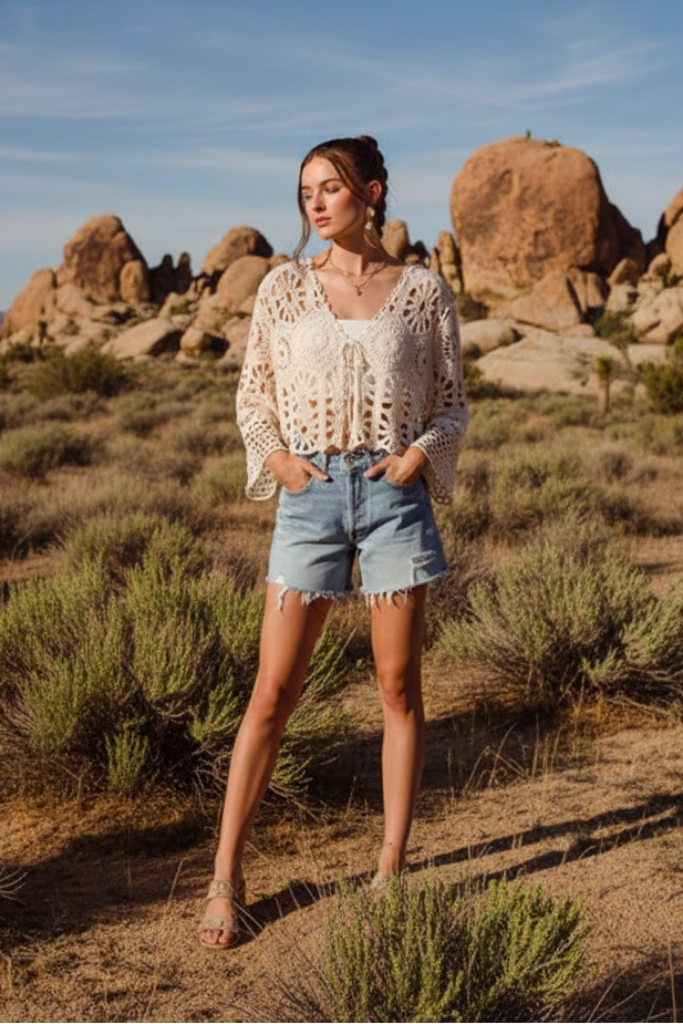 Cream crochet cardigan with denim shorts and desert landscape