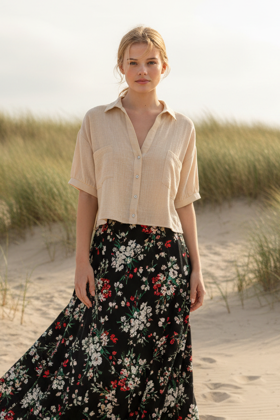Cream cropped button-up shirt with black floral maxi skirt and coastal beach background