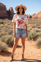 Cream cropped Let's go Cowgirls graphic tee with denim shorts and desert landscape