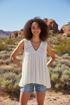 Cream white sleeveless babydoll top with eyelet lace detail and denim shorts with desert landscape
