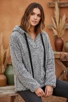 Gray fuzzy pullover hoodie on model with styled background
