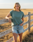 Hash jade rolled sleeve tee with denim shorts and western boho ranch background