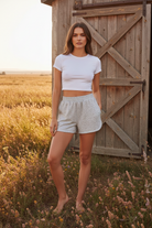 Heather grey dolphin hem sweat shorts with rustic barn wildflower meadow background