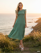 Jade green tiered midi dress with coastal cliff background