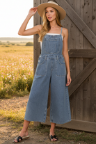 Medium wash wide leg denim overalls with rustic barn wildflower meadow background