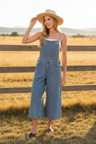 Medium wash wide leg denim overalls with western boho ranch background