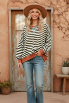 Olive green and cream striped sweater with rust trim on model
