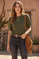 Olive green cable knit sweater on model with styled background