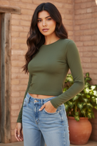 Olive green cropped long sleeve top on model with styled background