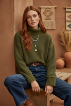 Olive green cropped turtleneck sweater on model with styled background