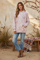 Pink camo hoodie on model with styled background