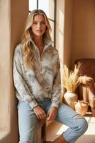 Sage green camo half-zip pullover on model with styled background