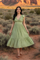 Sage green floral print midi dress with ruffle neckline and desert landscape