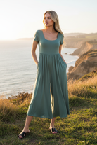 Sage green jumpsuit with coastal cliff background