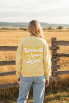 Soft yellow Spread the Love of Jesus graphic sweatshirt with western boho ranch background