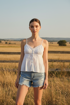 White lace-trimmed cami top with button detail and denim shorts with western boho ranch background