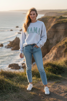 White "MAMA" graphic sweatshirt with coastal cliff background
